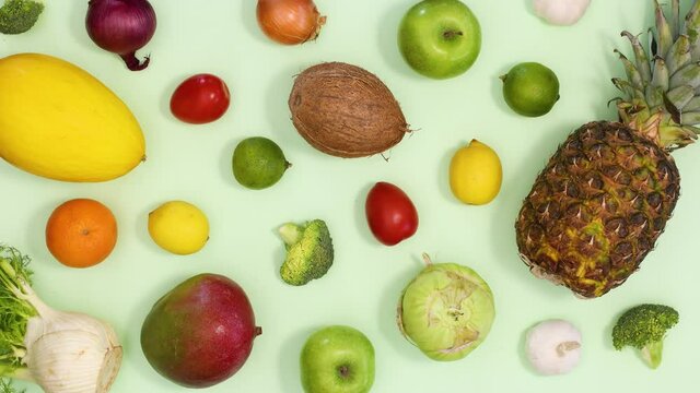 Healthy fresh fruits and vegetables make pattern on light green background. Stop motion