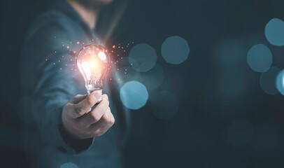 Businessman holding glowing lightbulb with light ray for creative thinking ideas and innovation concept.
