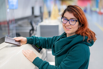 A woman at the check-in counter at the airport and gives her passport to buy a flight ticket