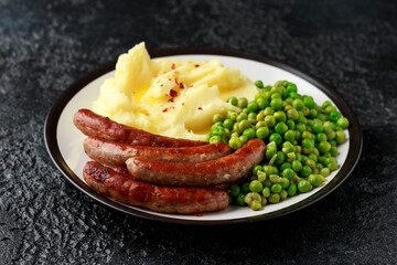 Pork Chipolata sausages with home cooked mashed potato and green peas
