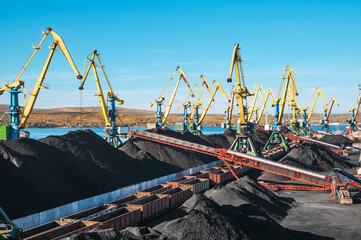huge amount of coal in the Murmansk commercial seaport. Coal is delivered here in industrial wagons, distributed throughout the port, unloaded, and then loaded onto sea dry cargo ships.