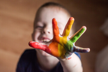 a little boy shows his rainbow-colored hands. the child drew a rainbow on his hands
