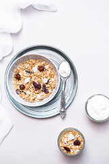 Granola with chia seeds, coconut, dry berries and yogurt in bowls on grey background, copy space. Concept of healthy breakfast menu 