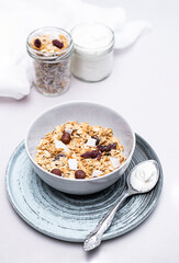 Granola with chia seeds, coconut, dry berries and yogurt in bowls on grey background, copy space. Concept of healthy breakfast menu 