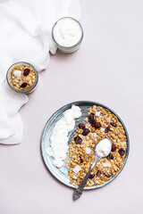 Granola with chia seeds, coconut, dry berries and yogurt in bowls on grey background, copy space. Concept of healthy breakfast menu 