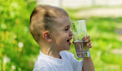 The child drinks clean water in summer. Selective focus.