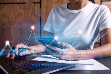 Businesswoman typing on computer in office. Fiancial graph hologram. Double exposure.