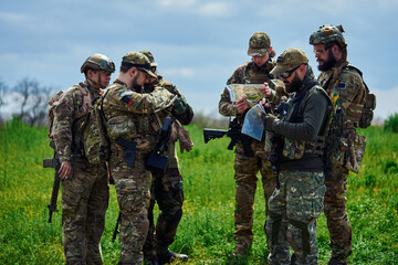 A group of military soldiers are examining the map