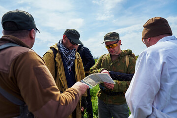 Airsoft players in military uniforms examine the map