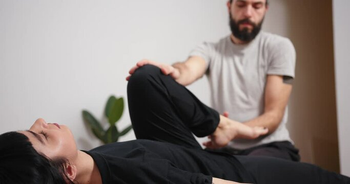 Mixed race latin woman having massage at home. Bearded man making yoga thai massage trigger point work shiatsu physical therapy fascia release