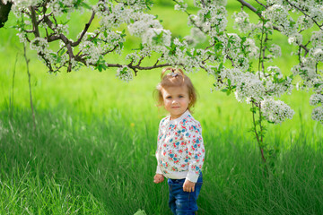 little girl stands in a flowering spring garden. seasonal allergies in children