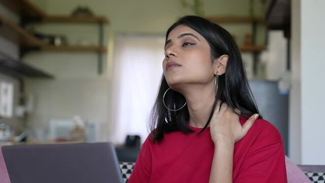 Asian Young businesswoman sits at work desk feeling fatigued,exhausted having neck pain and shoulder touching,self-massaging,and stretching with a painful face.Office Syndrome Concept.work from home.