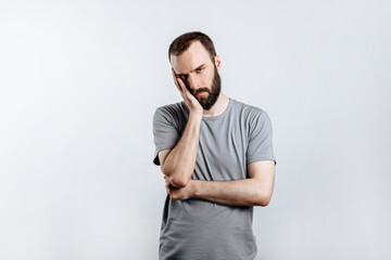 Portrait of handsome young man frowning while holding hands near head on white background with space for advertising mock up