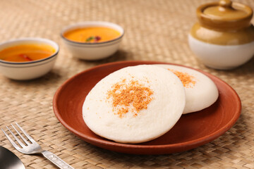 Thatte idli or Plate idly with sambar coconut chutney, chutney podi popular breakfast of Kerala South India Sri Lanka. Healthy steamed rice cakes steaming fermented batter black lentils and rice.