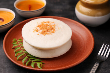 Thatte idli or Plate idly with sambar coconut chutney, chutney podi popular breakfast of Kerala South India Sri Lanka. Healthy steamed rice cakes steaming fermented batter black lentils and rice.
