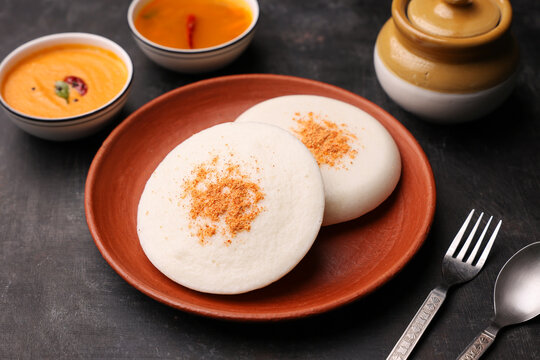 Thatte idli or Plate idly with sambar coconut chutney, chutney podi popular breakfast of Kerala South India Sri Lanka. Healthy steamed rice cakes steaming fermented batter black lentils and rice.