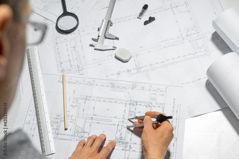 Poster the hands of a professional architect draw a sketch of a design project with a pencil. work table of