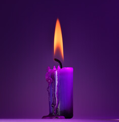 purple candle on a purple background, a bright orange light.