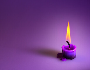 purple candle on a purple background, a bright orange light.