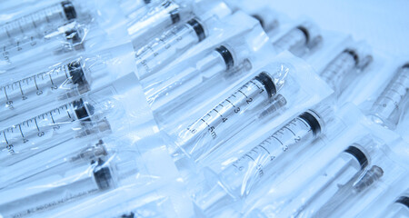 Medical syringes in a package. A bunch of unused, packaged syringes.Many new syringes lie strewn on a flat surface.