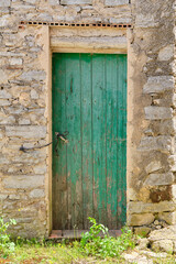 Facade of an old abandoned house with an old, rotten and green door.