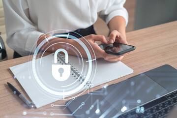 A woman programmer is browsing the Internet in smart phone to protect a cyber security from hacker attacks and save clients confidential data. Padlock Hologram icons over the typing hands. Formal wear