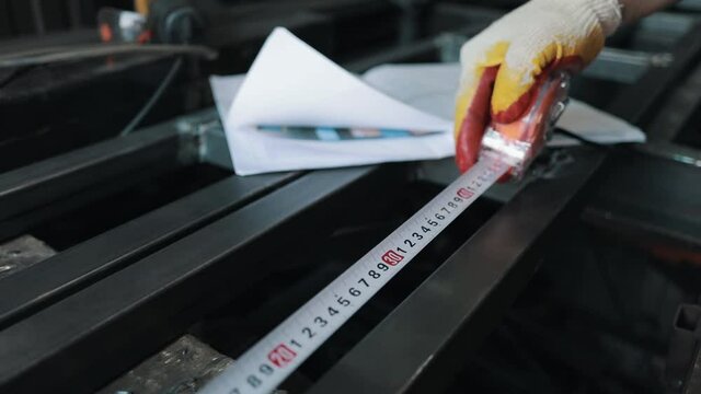 A worker measures a piece of metal. tape measure in motion close-up. roll measurement