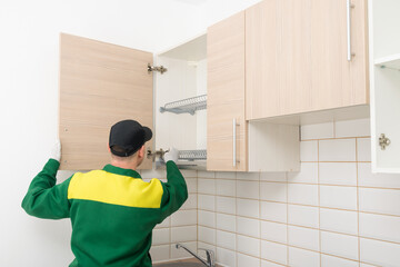 furniture assembly specialist hangs the fronts on the top cabinet of the kitchen unit, rear view