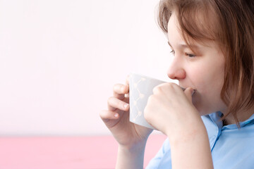 The girl in the blue shirt drinks, takes a sip from a large gray cup. Concept in the morning,...