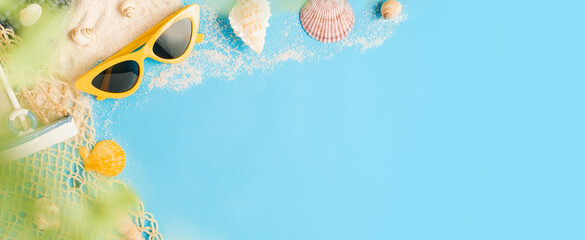 Tropical summer beach sea accessories objects,sunglasses,green straw bag,sailing and seashell over pastel blue background banner