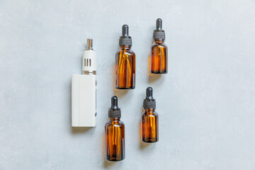 Vaping device e-cigarette electronic cigarette and liquid bottles on concrete stone grey background. Vape device for alternative smoking. Vaping shop concept. Gadget for vaper. Vaping accessories.
