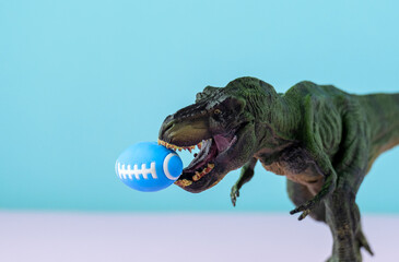 Big green dinosaur holding amirican football ball in mouth. Pastel background. Funny sports concept.