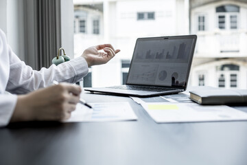 A businesswoman pointing at a laptop screen that opens the company's annual financial summary is examining the document together with the head of the finance department that made it. Financial concept