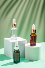 Glass cosmetic bottles with oil or serum for skin care on special podium on green color background. Natural skin care concept. sharp shadows