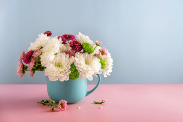 Summer bouquet of white chrysanthemum flowers in a blue cup on a blue background.