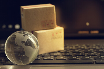Shopping online, e-commerce concept: Crystal globe with cardboard boxes on keyboard. depicts of purchase of products on internet used for worldwide international connections.
