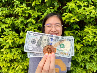 Asian Lady holding Golden Bitcoin and US Dollar Bank Note