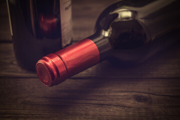 Two bottles of red wine lying on an old wooden table. Close up view, focus on the bottle of red wine