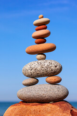 Rock zen pyramid of colorful pebbles on a background of blue sky