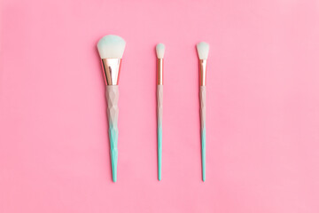 beautiful three makeup brushes on a pink background. tools for the work of a makeup artist. the concept of the sphere of beauty, decorative cosmetics