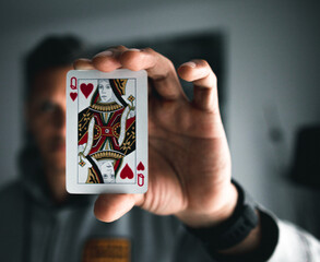 A young man holding a Queen of hearts card