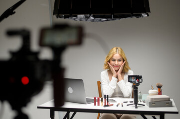 Behind the scenes young blonde woman entrepreneur working with laptop presents cosmetic products...