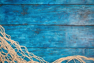 Fishing net on boho blue board background with copy space - obrazy, fototapety, plakaty