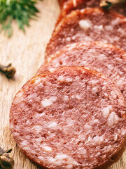 sliced pieces of salami sausage on wooden board, harmful fast food, fatty not healthy food, close-up,