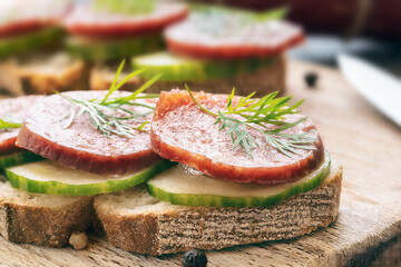 smoked sausage with vegetables on rye piece of bread on wooden board, harmful fast food, fatty not healthy food, close-up