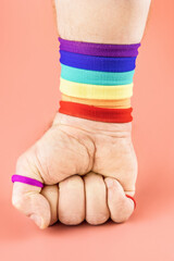hand clenched into fist in the color of rainbow on colored background, concept for the rights of LGBT people