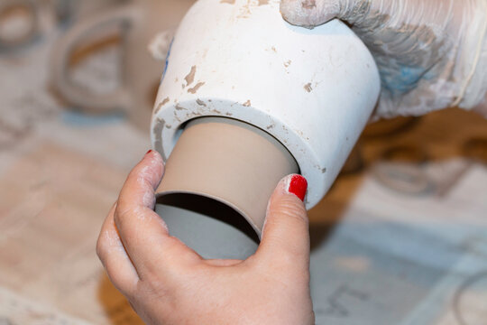 ceramic artist woman takes out the seramic cup from the mold