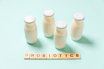 Small bottles with probiotics and prebiotics dairy drink on blue background. Production with...