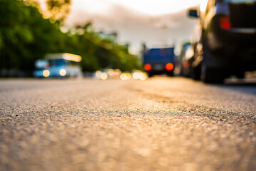 Setting sun in the suburbs, headlights of the approaching cars. View from the asphalt level