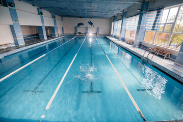 A young athlete trains and prepares for swimming competitions in the pool. Healthy lifestyle.